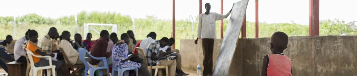 A child is an onlooker in a class for adults in a classroom in Juba, South Sudan