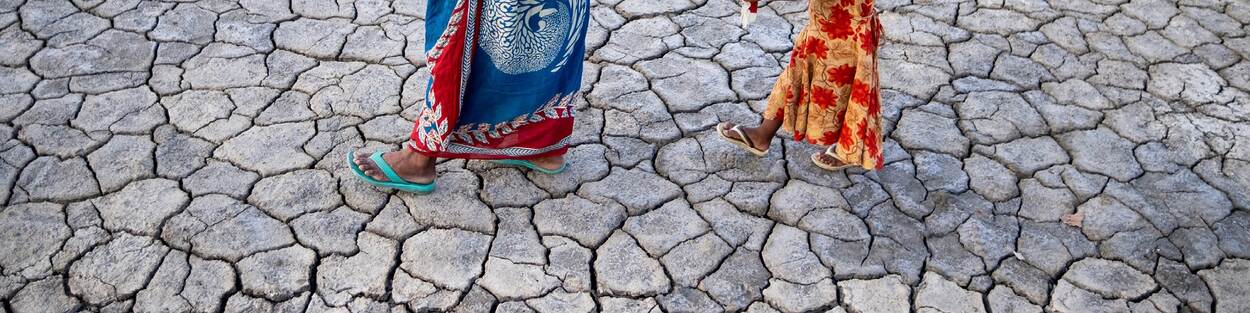 Vrouw en kind lopen over droge vlakte in Bangladesh